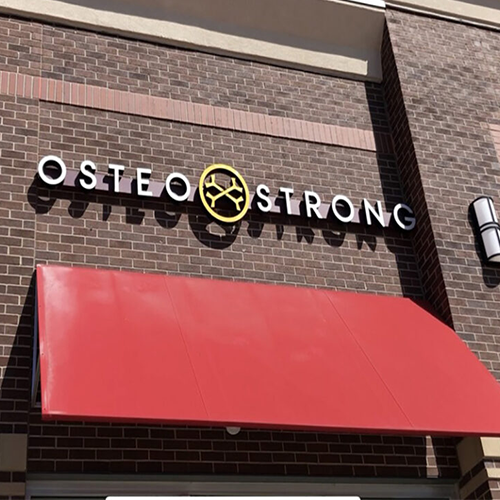 Channel letter sign for 'Osteo Strong' mounted on a raceway. Bold, capitalized sans-serif letters provide clear visibility. The raceway, blending with the building's façade, offers a neat, professional look, suitable for a health and wellness center.